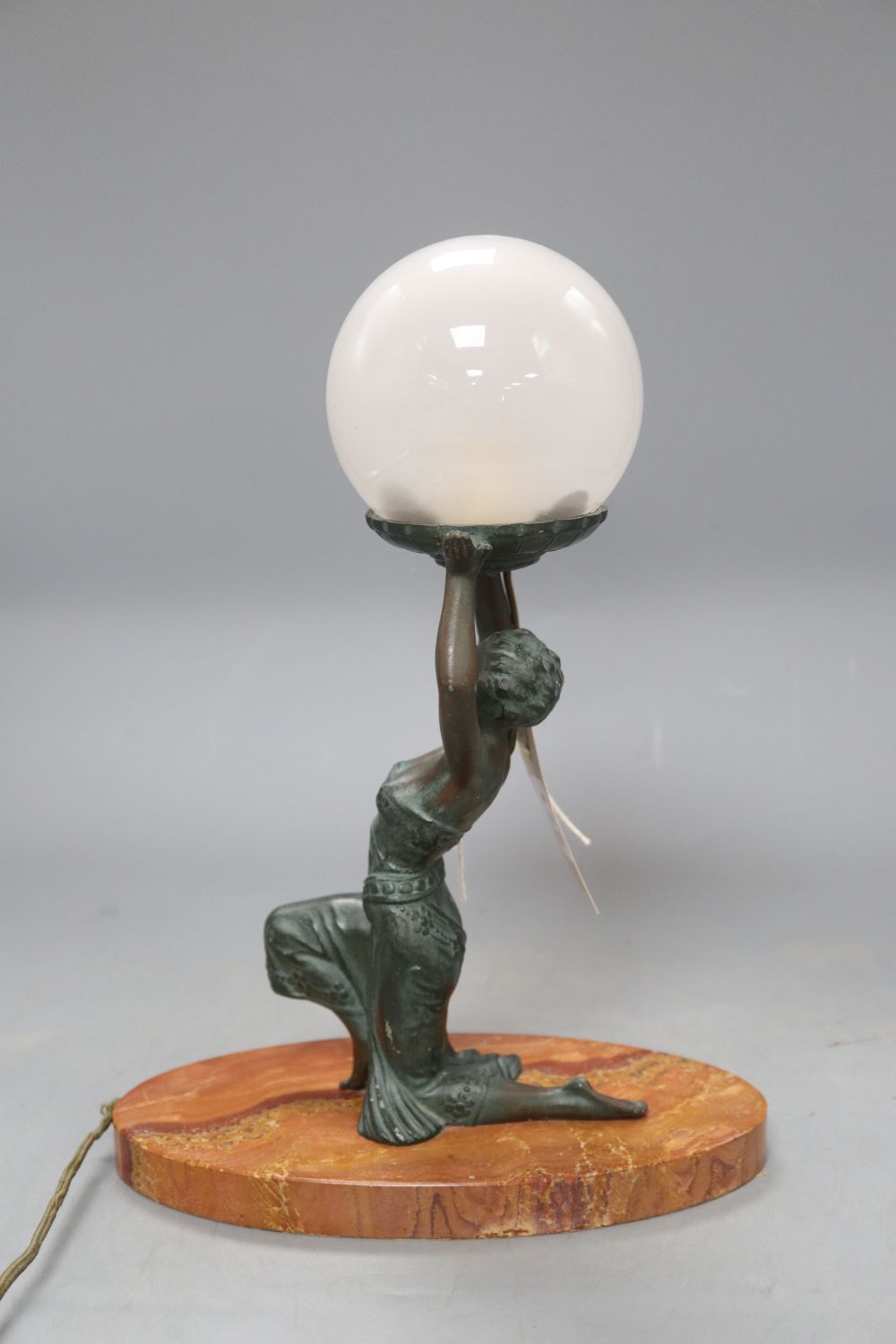 An Art Deco table lamp modelled as bronzed kneeling lady holding a globe, on oval rouge marble base, height 31.5cm